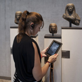 Frau mit Medienguide vor einem Objekt