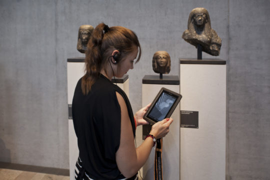 Frau mit Medienguide vor einem Objekt