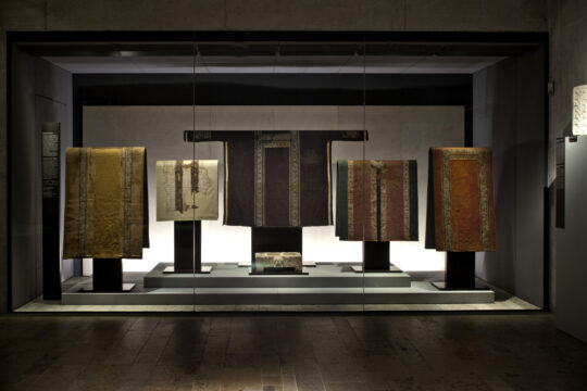 Blick in eine Vitrine, in der eine Reihe Tuniken ausgestellt sind.